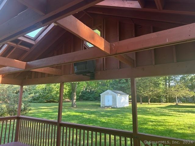deck with a storage shed, a lawn, and an outdoor structure