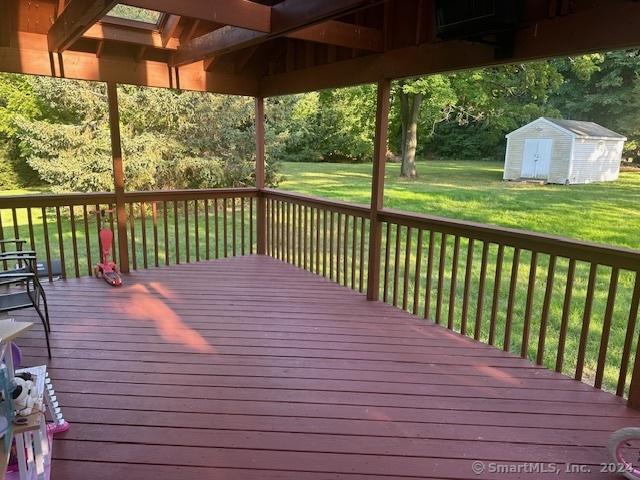 wooden deck featuring an outbuilding, a storage shed, and a yard