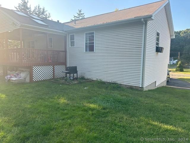 rear view of property featuring a yard and a deck