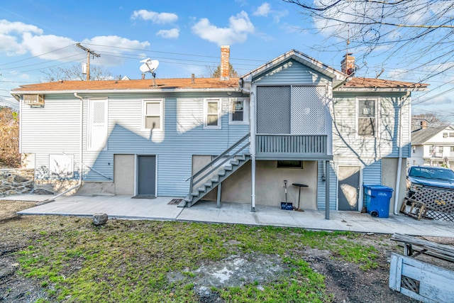 rear view of house with a patio area, a chimney, and stairs