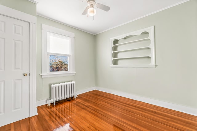 unfurnished room featuring radiator heating unit, ornamental molding, baseboards, hardwood / wood-style flooring, and ceiling fan