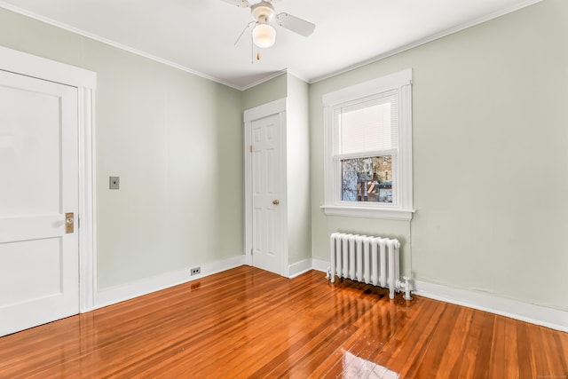 spare room with radiator heating unit, hardwood / wood-style floors, ceiling fan, baseboards, and ornamental molding