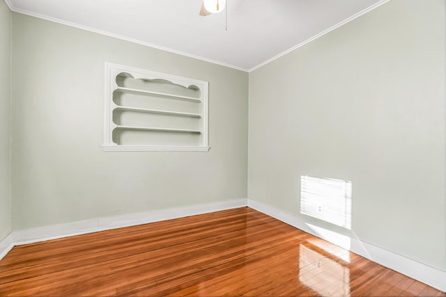 empty room featuring a ceiling fan, wood finished floors, built in features, baseboards, and ornamental molding