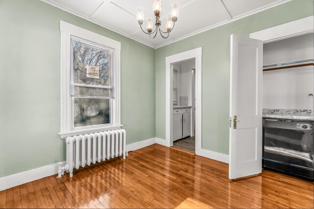 interior space with a chandelier, radiator heating unit, light wood finished floors, and baseboards