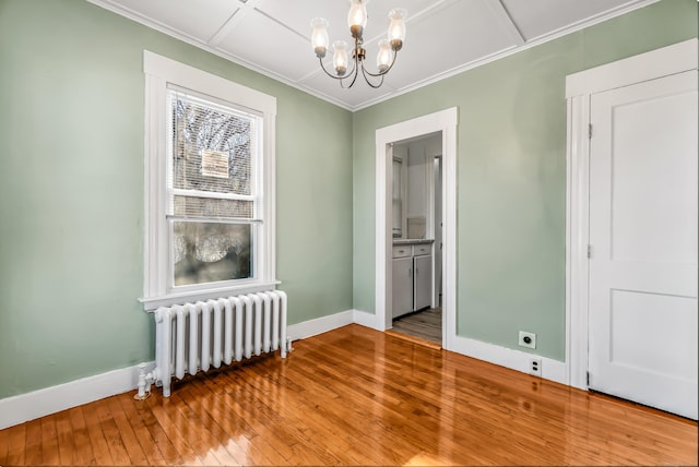 empty room with radiator, wood-type flooring, baseboards, and an inviting chandelier