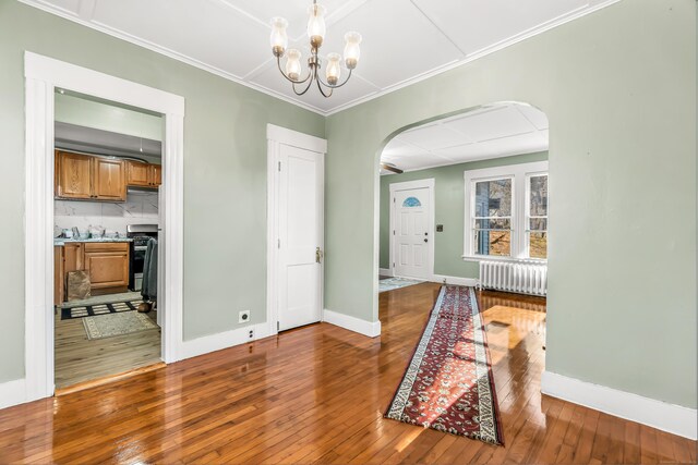 dining space with hardwood / wood-style flooring, radiator, arched walkways, and baseboards