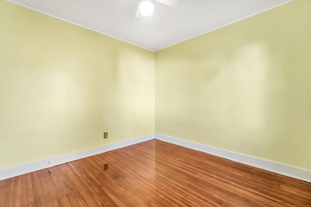 spare room featuring a ceiling fan, baseboards, ornamental molding, and wood-type flooring