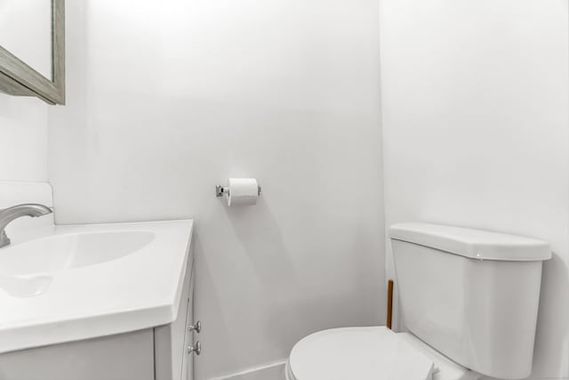 bathroom featuring baseboards, vanity, and toilet