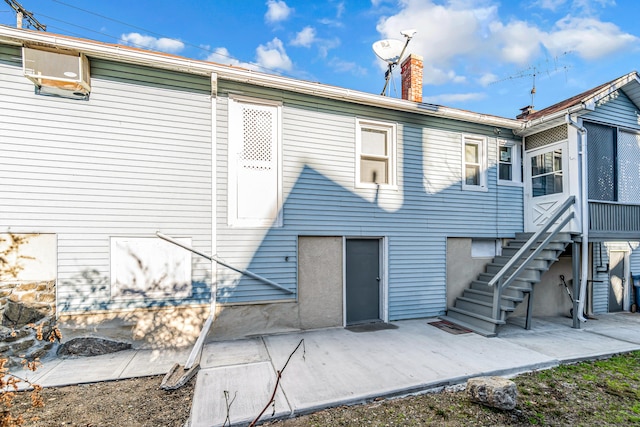 back of house featuring stairs, a patio area, and a chimney