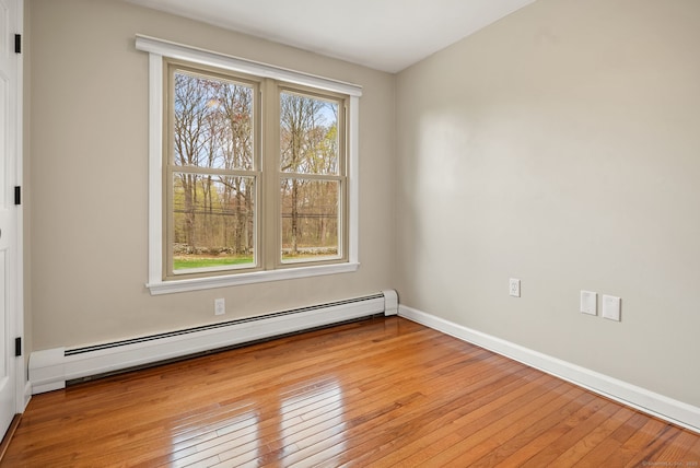 unfurnished room featuring baseboards, light wood-style flooring, and baseboard heating
