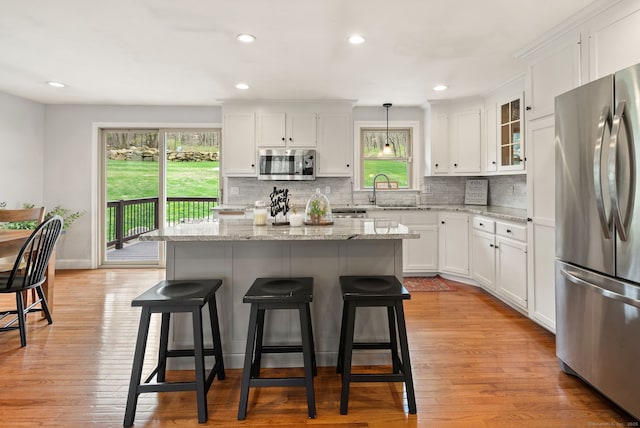 kitchen with a sink, appliances with stainless steel finishes, tasteful backsplash, and a kitchen bar
