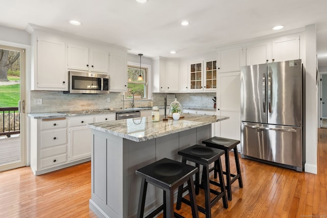 kitchen featuring glass insert cabinets, decorative backsplash, white cabinets, light wood-style floors, and stainless steel appliances