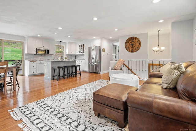 living room with an inviting chandelier, recessed lighting, and light wood finished floors