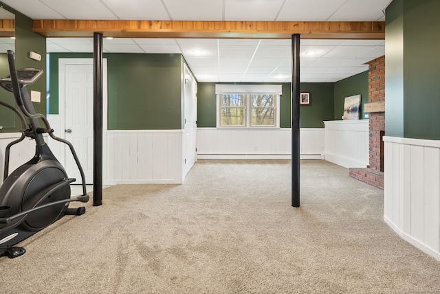 basement with carpet flooring, baseboard heating, and a wainscoted wall