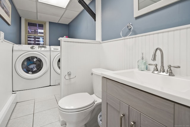 bathroom featuring wainscoting, toilet, a paneled ceiling, tile patterned floors, and separate washer and dryer