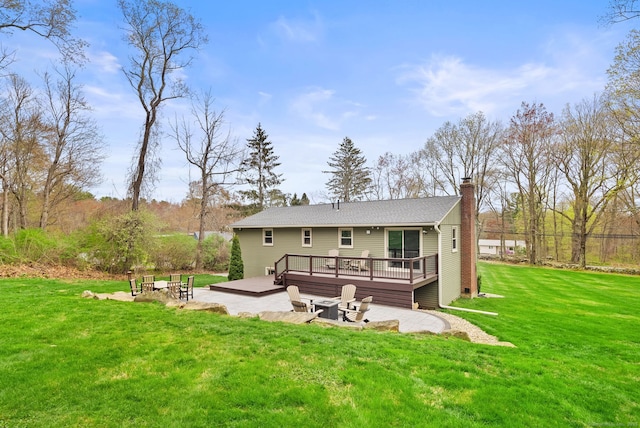rear view of property with a lawn, a patio, a chimney, and a deck