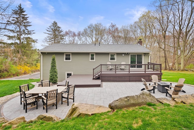 rear view of property featuring a patio, an outdoor fire pit, a wooden deck, and a chimney