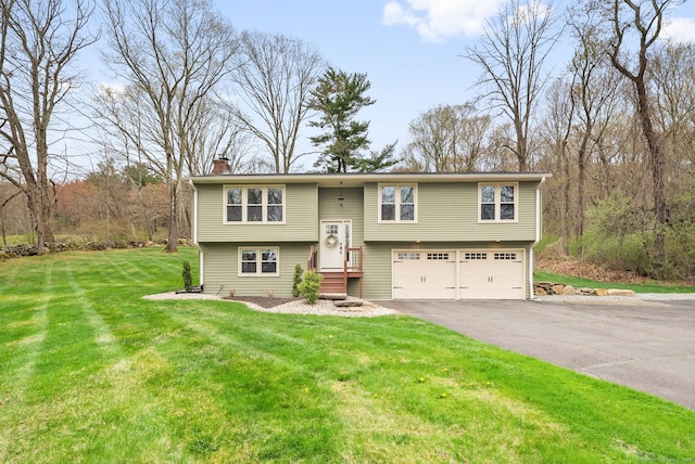 raised ranch with a garage, a chimney, driveway, and a front yard