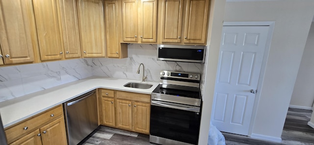 kitchen with a sink, decorative backsplash, appliances with stainless steel finishes, and dark wood-style floors