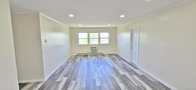 spare room featuring ornamental molding, baseboard heating, recessed lighting, and wood finished floors
