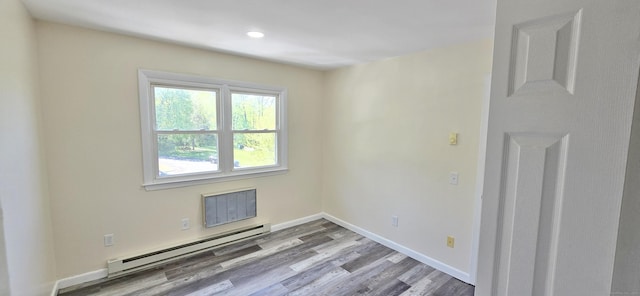spare room featuring visible vents, wood finished floors, baseboards, a baseboard radiator, and recessed lighting