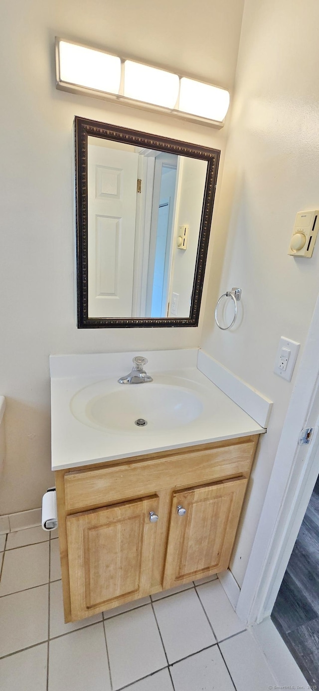 bathroom featuring vanity, baseboards, tile patterned floors, and toilet