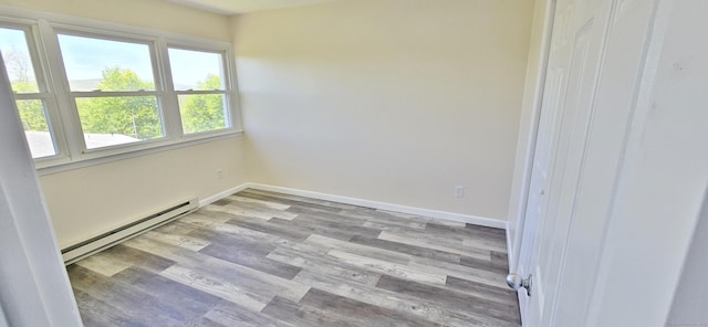 empty room with baseboards, wood finished floors, and baseboard heating