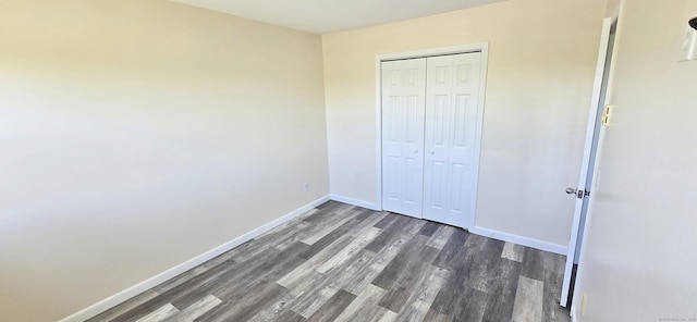 unfurnished bedroom featuring a closet, baseboards, and dark wood-type flooring