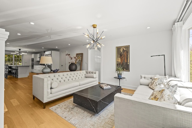 living room with light wood-style floors, a chandelier, recessed lighting, baseboards, and ornate columns