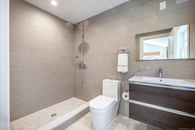 bathroom featuring vanity, tile walls, a tile shower, and toilet