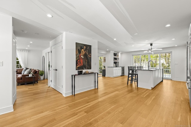 interior space featuring dark countertops, a sink, a ceiling fan, open floor plan, and a kitchen bar