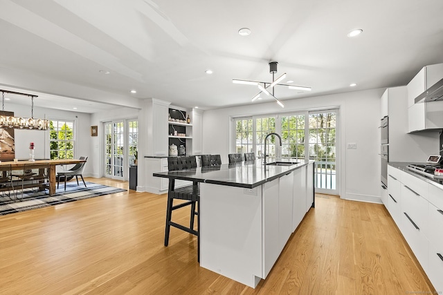 kitchen with white cabinets, open shelves, dark countertops, a sink, and recessed lighting
