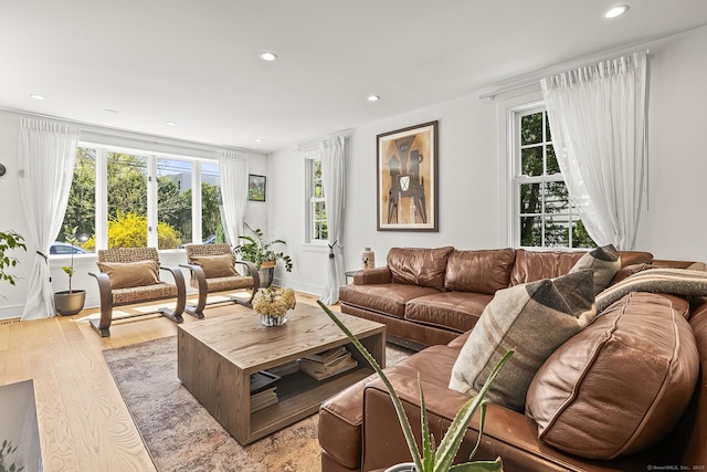 living room featuring recessed lighting, baseboards, and light wood-type flooring