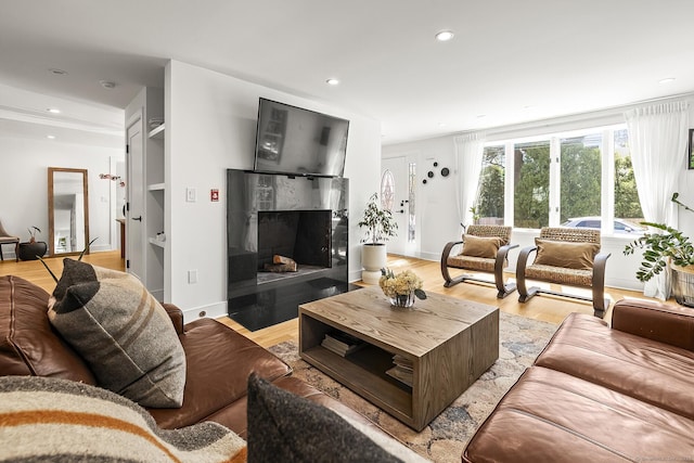 living area featuring recessed lighting, a high end fireplace, and light wood-style floors