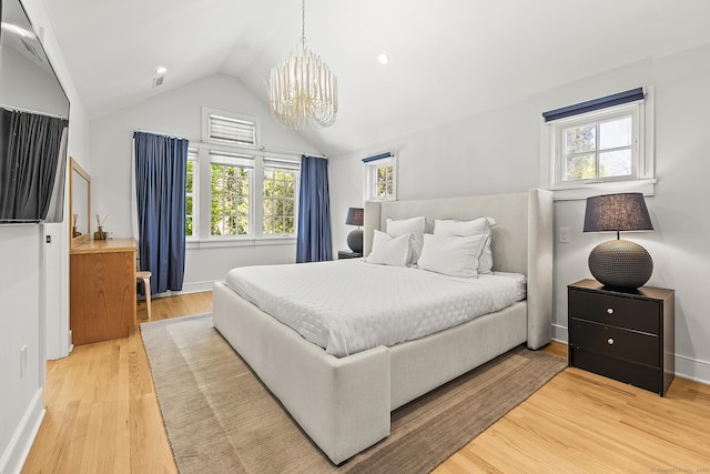 bedroom with a notable chandelier, multiple windows, light wood finished floors, and lofted ceiling