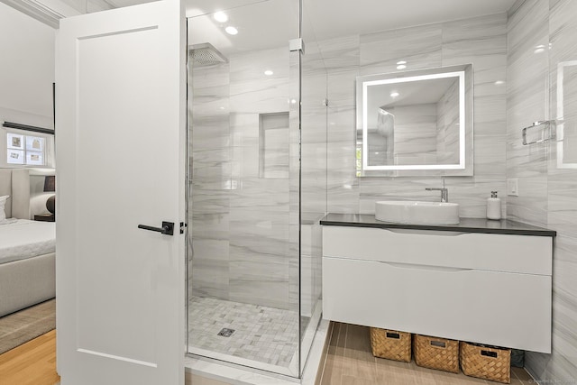 bathroom with tile walls, a shower stall, wood finished floors, and vanity