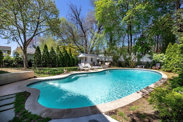 outdoor pool featuring a fenced backyard, an outbuilding, and a patio area