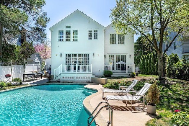 rear view of property featuring a fenced in pool, fence, a patio area, and a deck