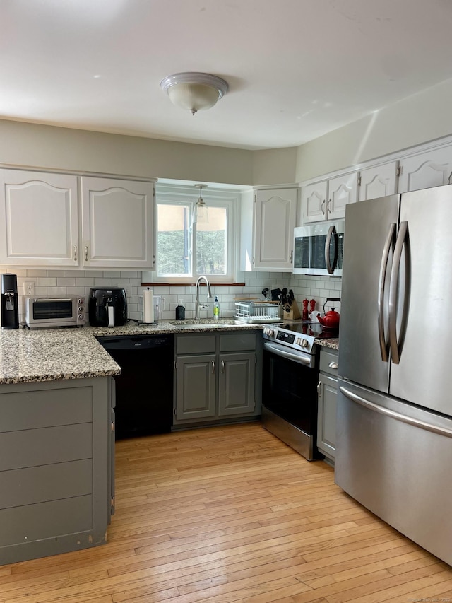 kitchen featuring decorative backsplash, a sink, stainless steel appliances, a toaster, and gray cabinets