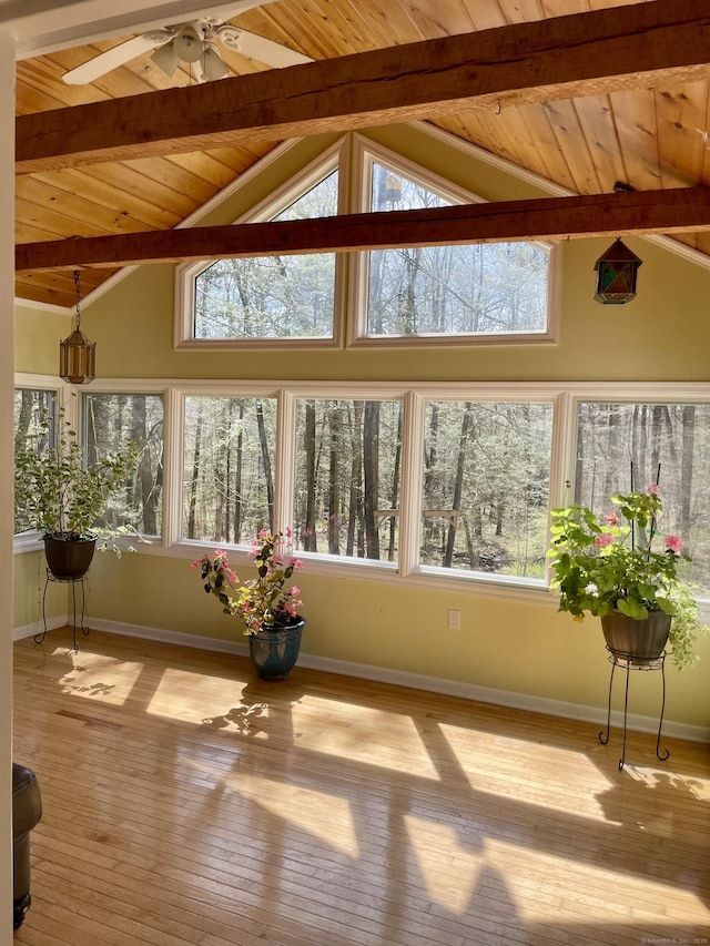 unfurnished sunroom featuring beamed ceiling, baseboards, hardwood / wood-style flooring, and wood ceiling