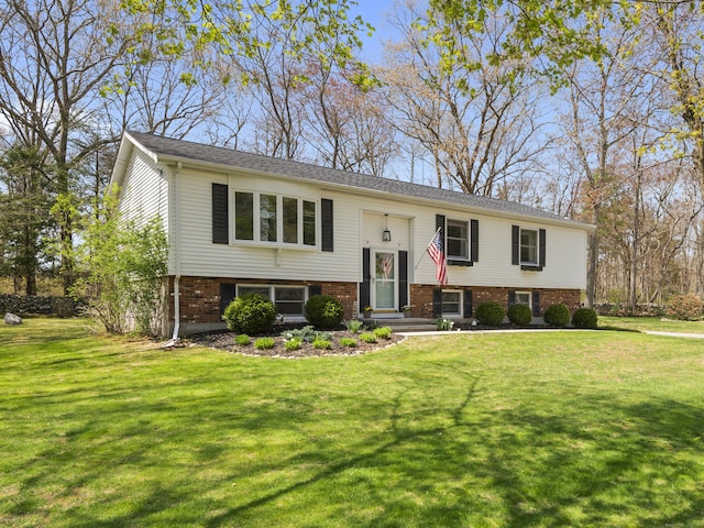 split foyer home with a front yard and brick siding