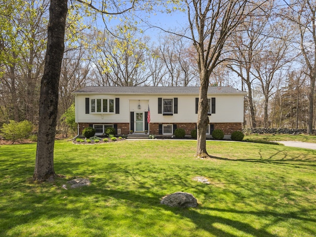 split foyer home featuring a front lawn and brick siding