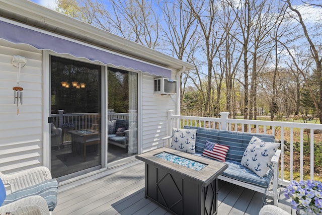 wooden deck featuring a wall mounted air conditioner and an outdoor living space with a fire pit