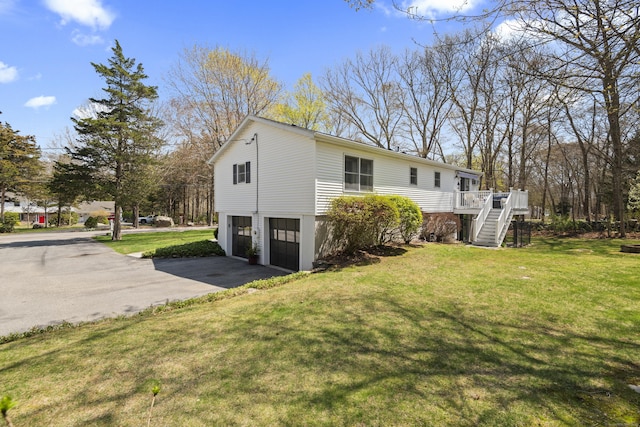 rear view of house with driveway, stairs, a deck, a lawn, and a garage