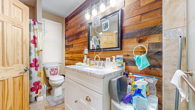full bathroom featuring wood walls, toilet, and vanity