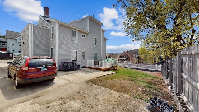 view of property exterior featuring a deck, a chimney, and a fenced backyard