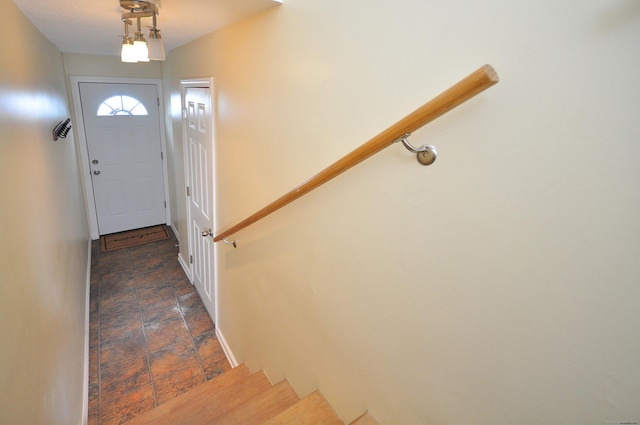 doorway to outside featuring stone finish floors, baseboards, and stairway