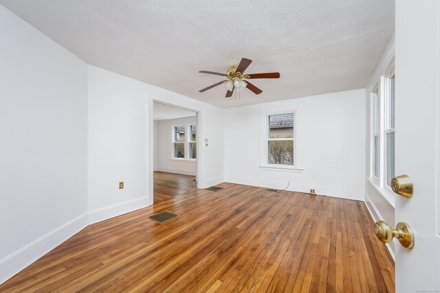 unfurnished room featuring ceiling fan, baseboards, wood finished floors, and visible vents