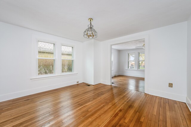 unfurnished room featuring visible vents, baseboards, light wood-style floors, and a chandelier
