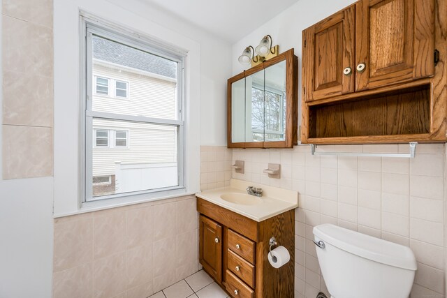bathroom with tile patterned flooring, toilet, vanity, and tile walls